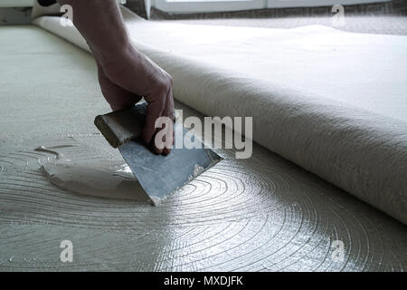 Craftsman while applying glue on a floor Stock Photo