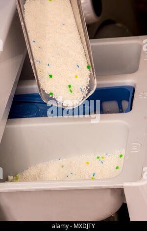woman is pouring powder detergent in wash machine to washing dirty clothes