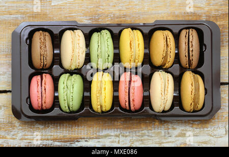 Colorful macaroons in box on wooden surface shot from the top Stock Photo