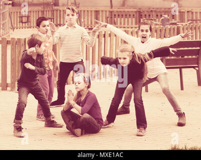 happy american children showing different figures during game in playground outdoors Stock Photo