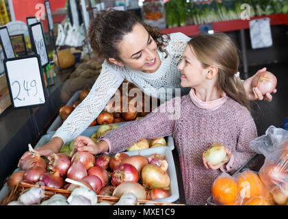 Portrait of happy  mother and smiling little girl purchasing veggies in market Stock Photo