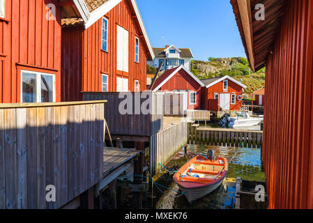 Kyrkesund, Tjorn, Sweden - May 18, 2018: Travel documentary of everyday life and place. Small motorboat moored between red wooden fishing sheds in the Stock Photo