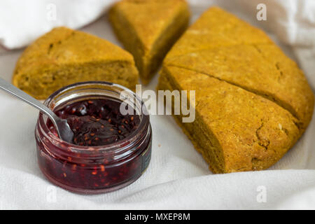 Freshly baked pumpkin spiced scones with Scottish raspberry jam. Sliced and displayed in a white linen tea towel. Stock Photo