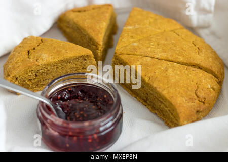 Freshly baked pumpkin spiced scones with Scottish raspberry jam. Sliced and displayed in a white linen tea towel. Stock Photo