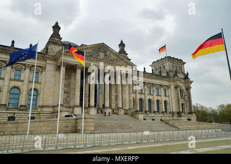 Berlin, Germany - April 14, 2018: Facade of Reichstag building with German and European Union Flags on the foreground under the dull sky Stock Photo