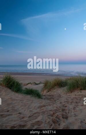 A path winding between the dunes down to a beach in the early morning Stock Photo