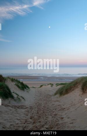 A path between the dunes down to a beach in the early morning Stock Photo