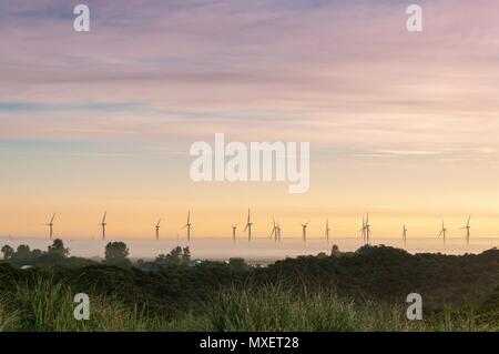 Wind turbines rising out of the mist at sunrise on a summer's morning Stock Photo