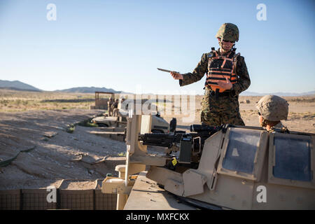 MARINE CORPS AIRGROUND COMBAT CENTER TWENTYNINE PALMS, California – Capt. Liz Hall, the logistics operations officer-in-charge with the Tactical Training Exercise Control Group, assists a Marine who is firing a Browning M2 .50 Caliber machine gun at Range 106A aboard Marine Corps Air Ground Combat Center, Twentynine Palms, California, May 2, 2017. Vehicle gunners with the logistics combat element of Marine Air Ground Task Force 3 conducted a live-fire shoot utilizing vehicle mounted weapon systems during Integrated Training Exercise 3-17. ITX is a training evolution conducted five times a year Stock Photo