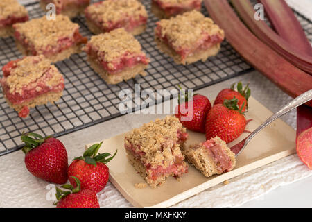 Healthy slices of red summer fruits bars served on a handmade ceramic plate. A delicious freshly baked dessert with strawberries and rhubarb. Stock Photo