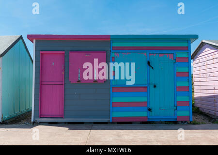a brightly coloured stripey beach hut painted in the shabby chic style on the coast of the isle of wight at bembridge beach. pink, blue, green paint. Stock Photo