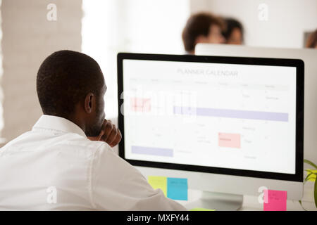 African American worker planning work schedule using desktop pla Stock Photo