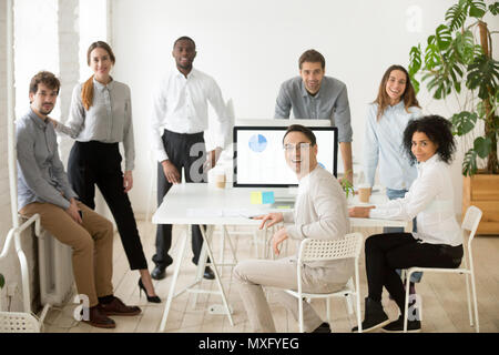 Multiracial team with group leader posing smiling at camera Stock Photo