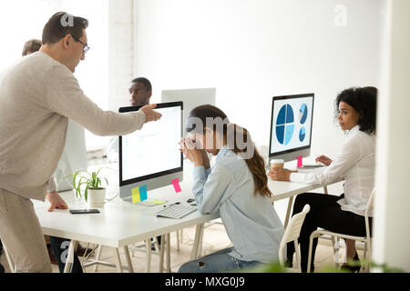 Mad middle aged boss lecturing female young employee in office Stock Photo