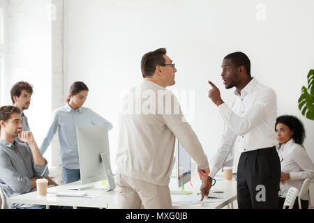 Angry black worker disputing with older Caucasian colleague Stock Photo