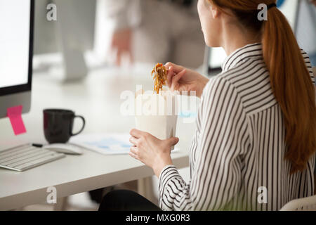 Female employee eating Asian noodles during office work break  Stock Photo