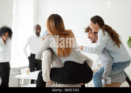 Laughing colleagues having piggyback ride at office Stock Photo
