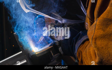 Man tig welding steel cast plates with brilliant bright white star burst bloom of lights Stock Photo