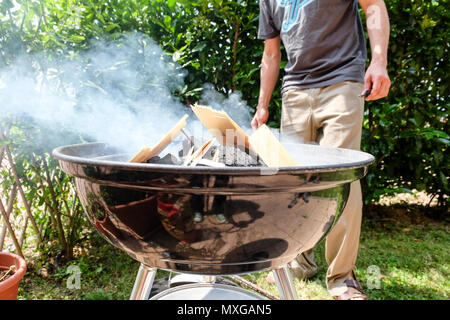 A sunny  day in the garden, starting the fire in the grill and then grilling meat with friends Stock Photo