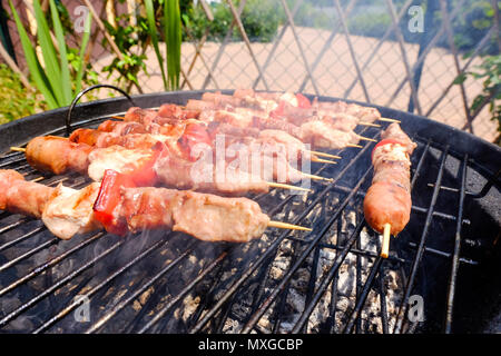 A sunny  day in the garden, starting the fire in the grill and then grilling meat skewers with friends Stock Photo