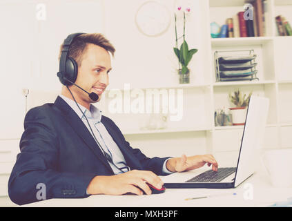Laughing man talking on headset at company office Stock Photo