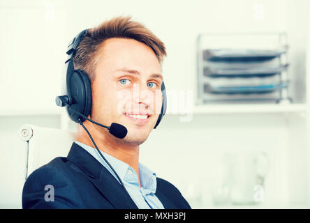 Laughing young man talking on headset at company office Stock Photo