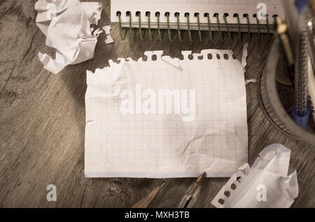 Empty crumpled pages and notebook lying on wooden surface Stock Photo