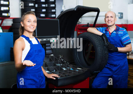 Two adult technicians working on wheel balancing machinery in car service Stock Photo