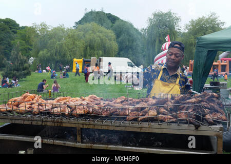 West Indian man cooking Jerk Chicken on barbecue in Wardown Park, Luton, England, UK Stock Photo