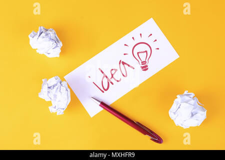 Paper with 'idea' text and crumpled paper balls on yellow background. Brainstorming concept Stock Photo