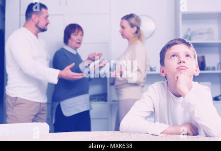 Sad desperate little boy during parents quarrel in home interior Stock Photo