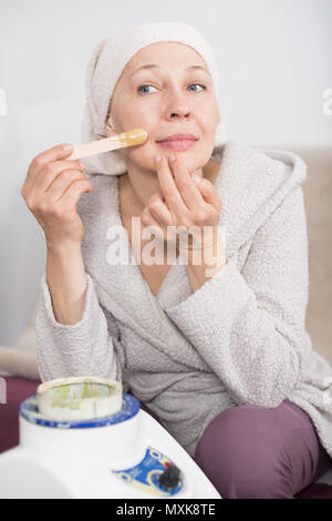 Mature woman getting body hair removed at home Stock Photo