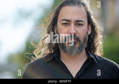 Mature handsome bearded multi-ethnic businessman with long hair in the streets outdoors Stock Photo