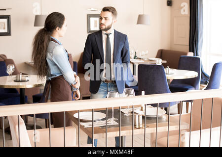 Frowning restaurateur talking to waitress Stock Photo