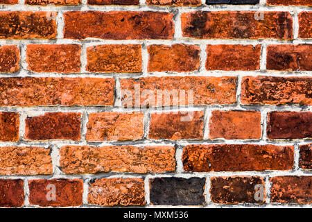 Detail of old and weathered grungy red brick wall marked by the long exposure to the elements as texture background. Stock Photo