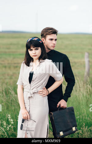 A cute young guy stands next to a pretty girl in whose hands a business bag Stock Photo