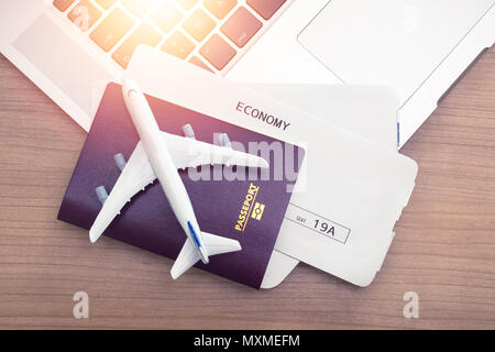 Two tickets are on the table with sunlight , laptop and passport . buying online ticket booking for travel concept Stock Photo