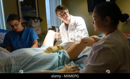 U.S. Navy Lt. Cmdr. Rozalyn Love, center, shows Lt. Jessica Dalrymple, left, and Lt. Christine Johnson how to perform a uterine massage during a simulated postpartum hemorrhage event at U.S. Naval Hospital Guam, Nov. 16, 2016.  The training teaches hospital staff a variety of ways to handle these types events, including quantative measurement of blood loss, which leads to prompt and appropriate treatment. (U.S. Navy photo by USNH Guam Public Affairs/Released) Stock Photo