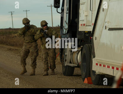 (From left) Senior Airman Dustin Silc and Staff Sgt. Tyler Chronister, 791st Missile Security Forces Squadron convoy response force members, perform a perimeter sweep of a payload transporter during a recapture and recovery exercise at the missile complex, N.D., Nov. 16, 2016. During the simulated scenario, defenders recovered an asset that was taken over by hostile forces. (U.S. Air Force photo/Senior Airman Apryl Hall) Stock Photo