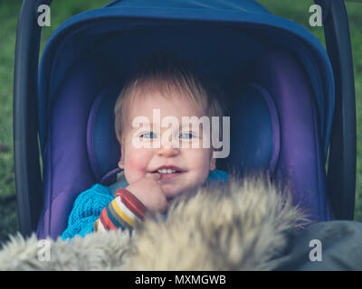 A cute little baby is sitting in a stroller outside Stock Photo