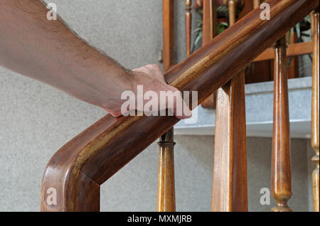 Male hand holding the banister walking upstairs Stock Photo