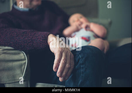 A grandfather is sitting in a chair at home with his grandson Stock Photo