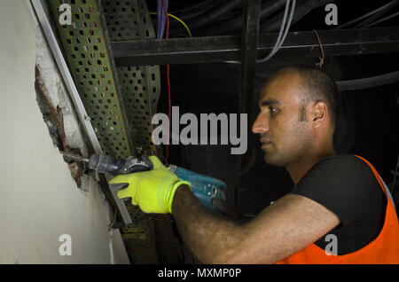 Man using a jackhammer to drill into wall Stock Photo