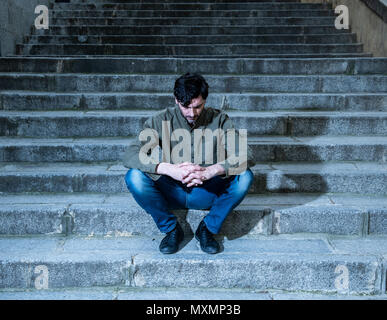 latin man stressed from work sitting on steps outside feeling anxiety in adult cause of depression and problem in living that makes you feel lonely, s Stock Photo