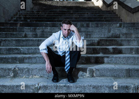 young business man crying abandoned lost in depression sitting on the street stairs suffering emotional pain, sadness in a mental health concept photo Stock Photo