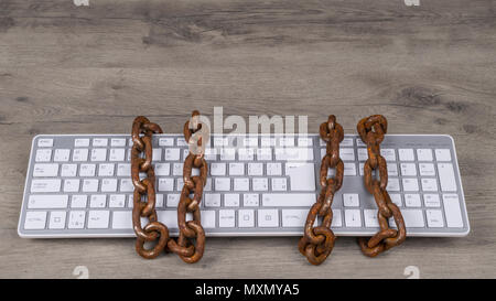 Computer keyboard tied with rusty chain. Old vintage chains on input device for digital informations. Concept of censorship, spy, cyber security, GDPR. Stock Photo
