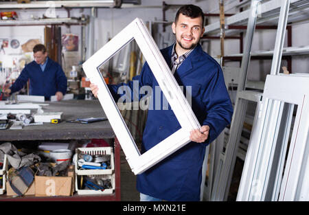 Two smiling positive careful workmen inspecting PVC manufacturing output in workshop Stock Photo