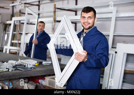 Two cheerful positive careful workmen inspecting PVC manufacturing output in workshop Stock Photo