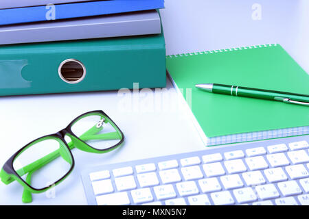 Work place table with folders file on it and modern laptop, pen, glasses and textbook lying near on a white background. Stock Photo