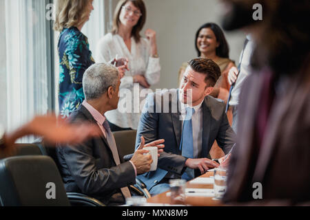 Two male businessmen talking during a conference. One businessman is making some notes. Stock Photo